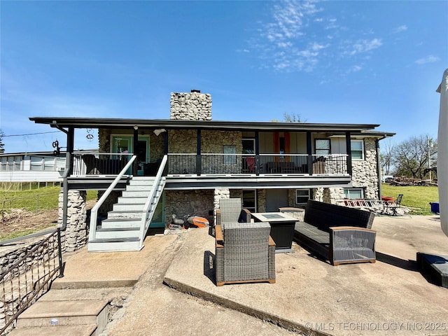 exterior space with a patio, a chimney, stone siding, an outdoor living space with a fire pit, and stairs