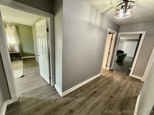 hallway featuring baseboards and dark wood finished floors