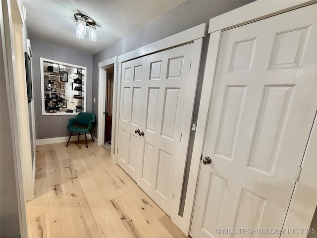 hallway with light wood-style flooring and baseboards