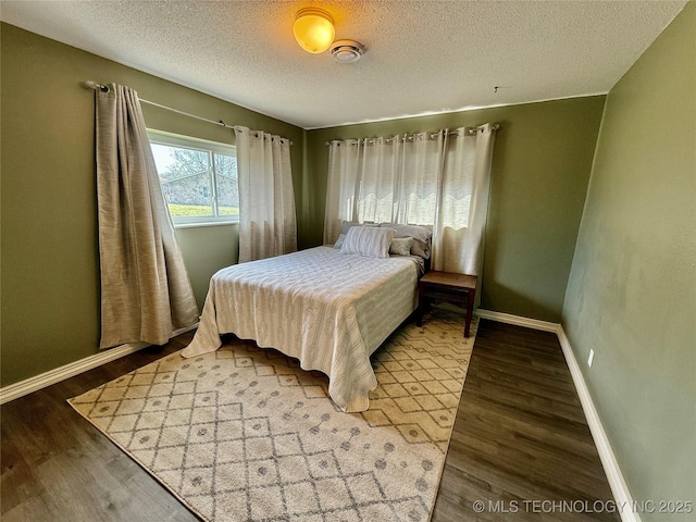 bedroom with baseboards, wood finished floors, and a textured ceiling