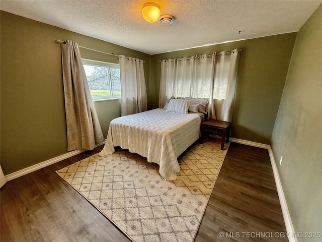 bedroom with baseboards, wood finished floors, and a textured ceiling