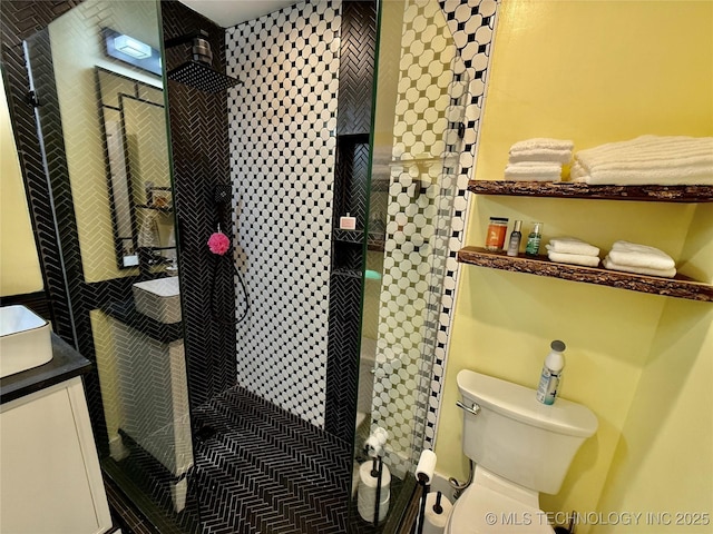 full bathroom with vanity, a tile shower, and toilet