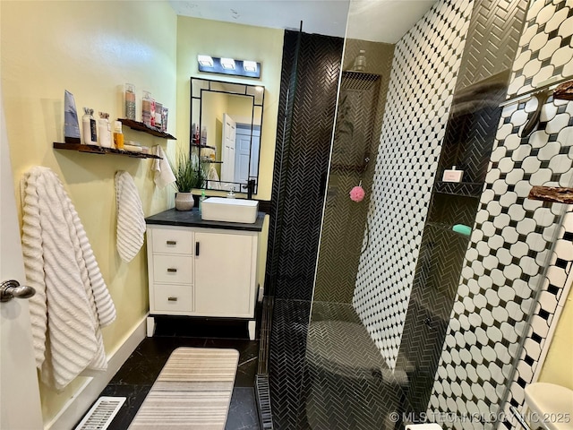 full bathroom with a tile shower, vanity, baseboards, and visible vents