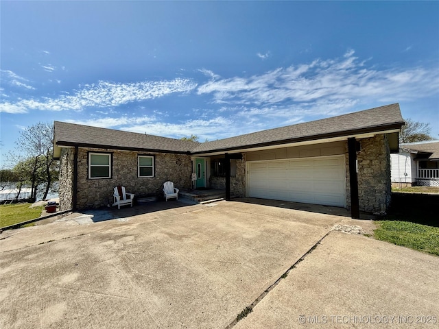 ranch-style home featuring driveway, stone siding, and an attached garage