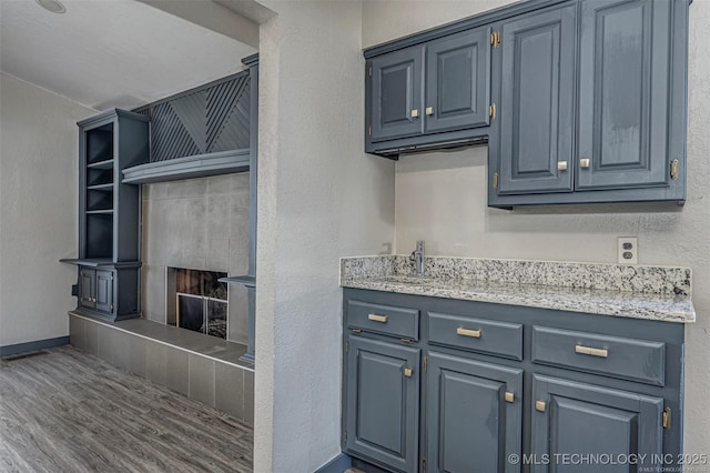 804 S Sooner Rd, Midwest City, OK 73110 - kitchen featuring blue cabinets, open shelves, wood finished floors, and a fireplace