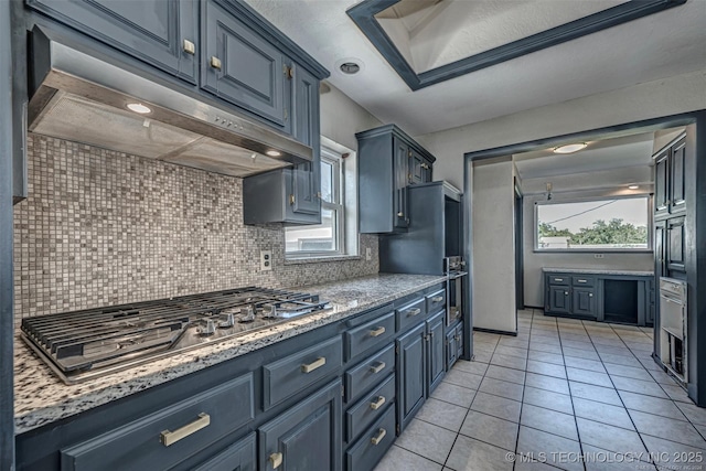804 S Sooner Rd, Midwest City, OK 73110 - kitchen with refrigerator, stainless steel gas cooktop, under cabinet range hood, light tile patterned flooring, and backsplash