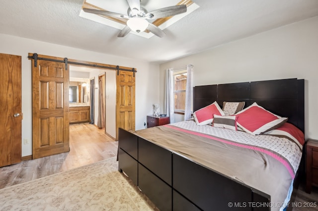 1604 S Chestnut Ave, Broken Arrow, OK 74012 - bedroom featuring light wood finished floors, a barn door, and a ceiling fan