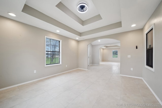 15338 S Brewster Rd, Mounds, OK 74047 - spare room featuring arched walkways, baseboards, light tile patterned floors, and a raised ceiling