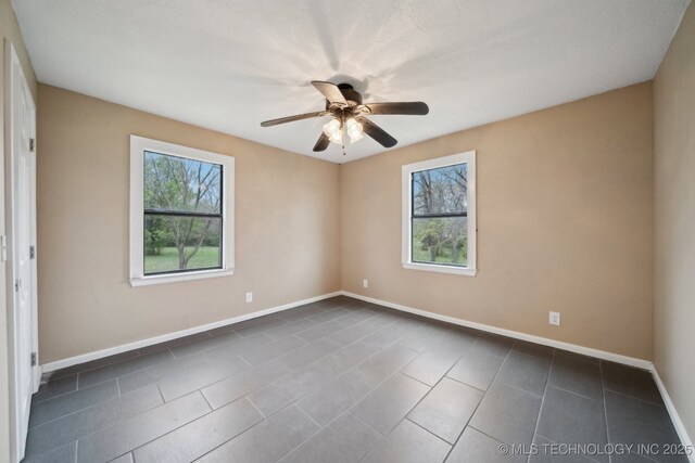 15338 S Brewster Rd, Mounds, OK 74047 - spare room featuring a ceiling fan, baseboards, and dark tile patterned floors
