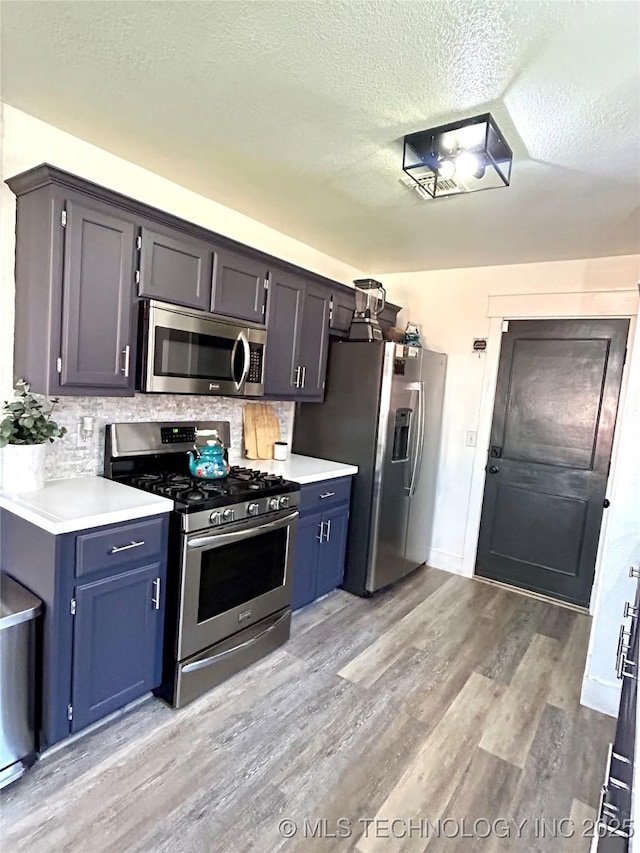 1110 S Catalina Dr, Oologah, OK 74053 - kitchen with a textured ceiling, light countertops, stainless steel appliances, light wood finished floors, and decorative backsplash