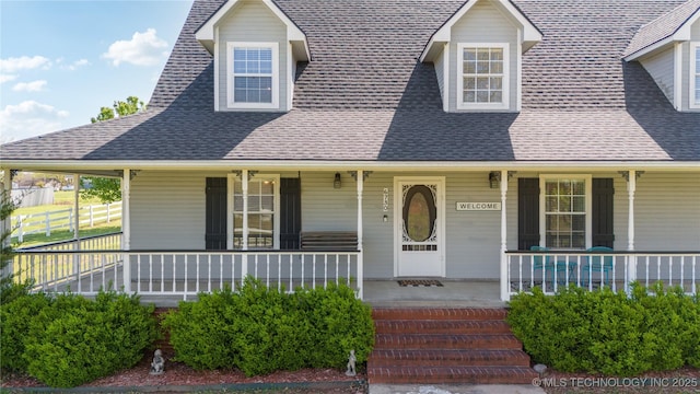 view of front of home featuring roof with shingles, a porch, and fence