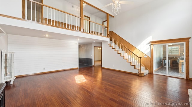 unfurnished living room with wood finished floors, ceiling fan, baseboards, and stairs