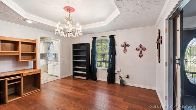 unfurnished office featuring crown molding, a tray ceiling, a chandelier, baseboards, and hardwood / wood-style flooring