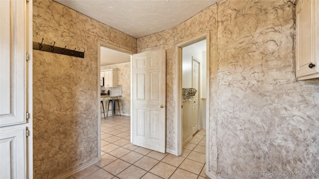 hallway with a textured ceiling and light tile patterned floors