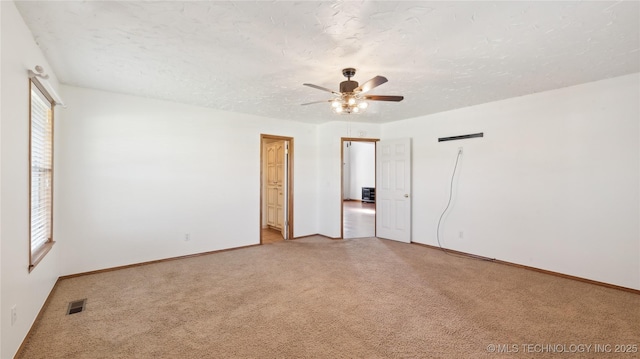 spare room with baseboards, a textured ceiling, visible vents, ceiling fan, and light colored carpet