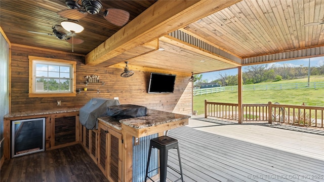 wooden deck featuring area for grilling, an outdoor kitchen, a yard, a ceiling fan, and fence