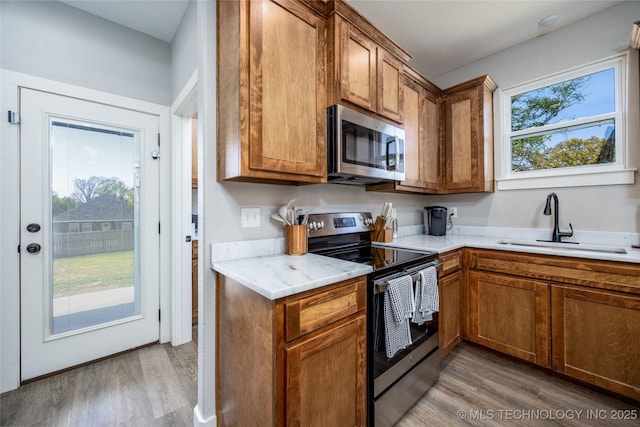 440 W 2nd St, Silo, OK 74701 - kitchen with a sink, light wood-style flooring, appliances with stainless steel finishes, and brown cabinets