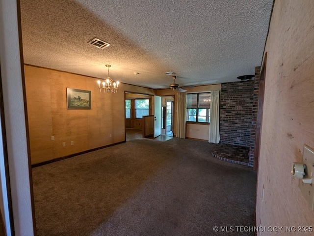 unfurnished living room with carpet floors, a textured ceiling, visible vents, and ceiling fan with notable chandelier