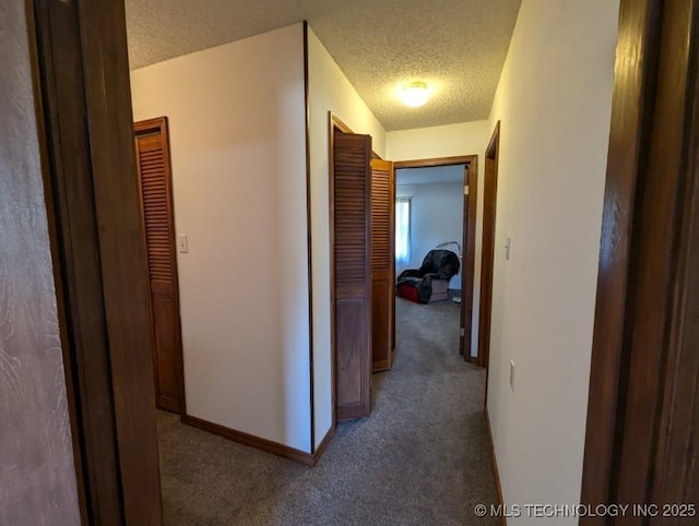 corridor featuring carpet flooring, a textured ceiling, and baseboards