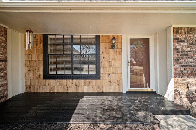entrance to property featuring brick siding and a porch