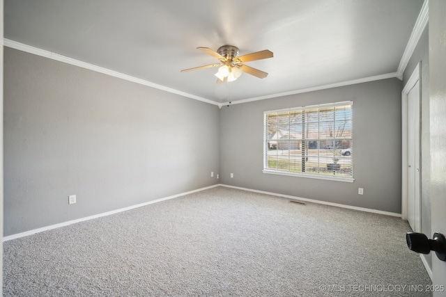 carpeted empty room with ornamental molding, visible vents, ceiling fan, and baseboards