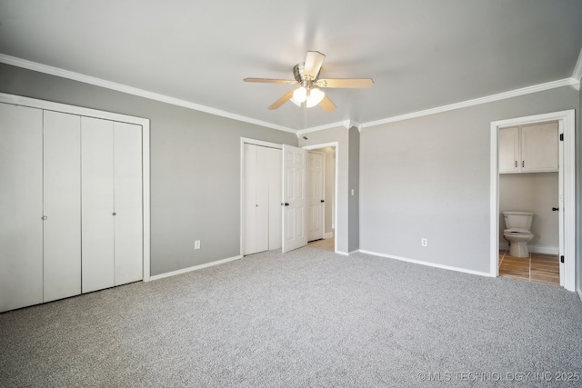 unfurnished bedroom with carpet, two closets, crown molding, and baseboards