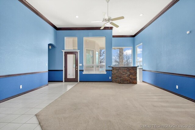 11746 Giorgio Dr, Skiatook, OK 74070 - empty room featuring baseboards, arched walkways, ceiling fan, crown molding, and tile patterned flooring