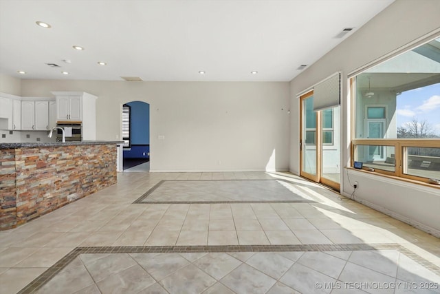 11746 Giorgio Dr, Skiatook, OK 74070 - unfurnished living room featuring recessed lighting, arched walkways, visible vents, and light tile patterned flooring