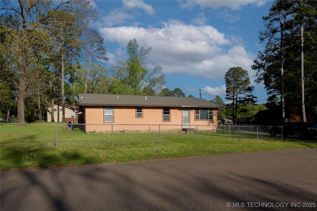 view of front of property featuring fence private yard, a front lawn, and metal roof