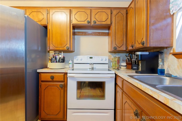 612 W Circle Dr, Broken Bow, OK 74728 - kitchen with electric stove, freestanding refrigerator, brown cabinets, and light countertops
