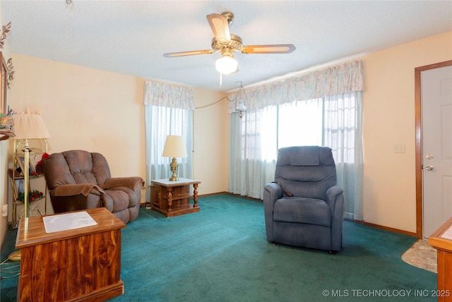 living area featuring baseboards, ceiling fan, carpet flooring, and a textured ceiling