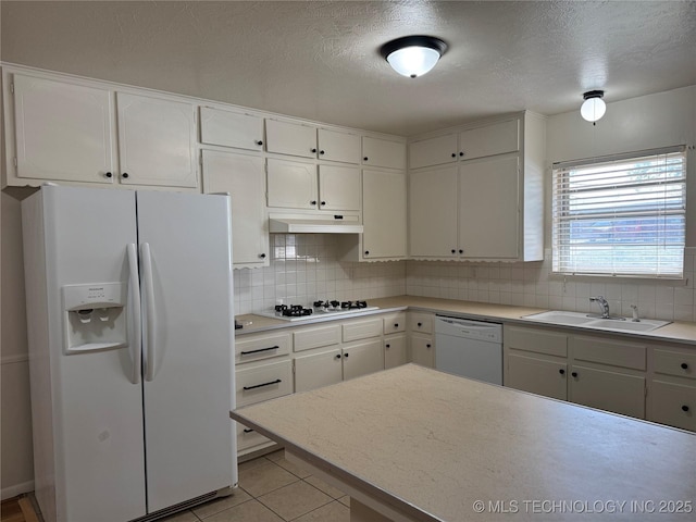 kitchen with tasteful backsplash, under cabinet range hood, a sink, and white appliances