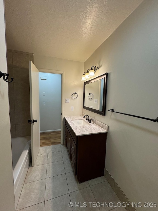 bathroom featuring tile patterned floors, vanity, baseboards, and a textured ceiling