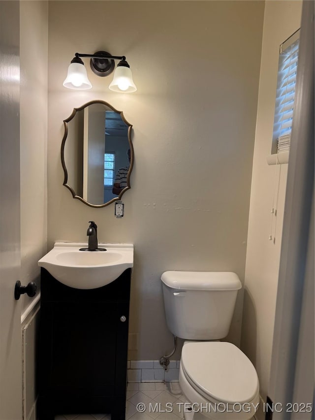 bathroom featuring tile patterned floors, vanity, baseboards, and toilet