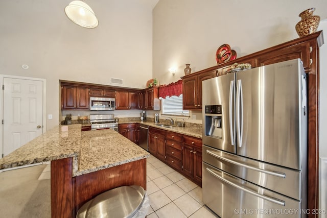 4932 W Commercial St, Broken Arrow, OK 74012 - kitchen with appliances with stainless steel finishes, a high ceiling, a sink, light tile patterned flooring, and light stone counters