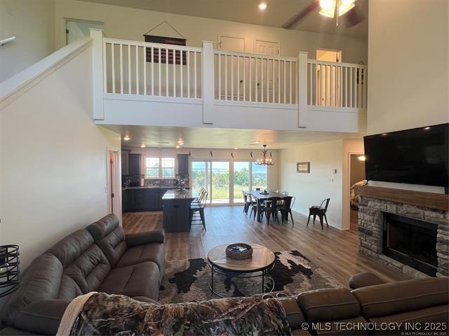 2241 231st St, Buffalo Valley, OK 74571 - living area with a fireplace, a high ceiling, wood finished floors, and ceiling fan with notable chandelier