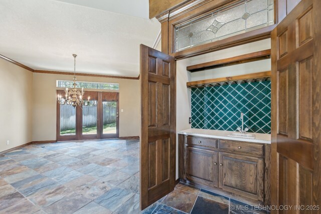 10126 S Granite Ave, Tulsa, OK 74137 - kitchen featuring baseboards, a sink, a chandelier, stone tile floors, and ornamental molding
