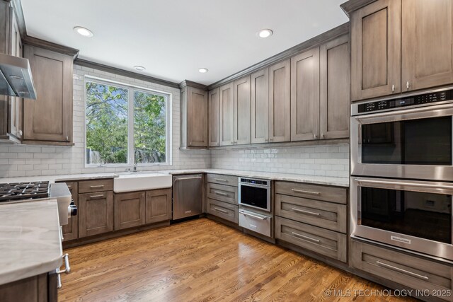 10126 S Granite Ave, Tulsa, OK 74137 - kitchen featuring appliances with stainless steel finishes, a sink, backsplash, recessed lighting, and light wood-type flooring