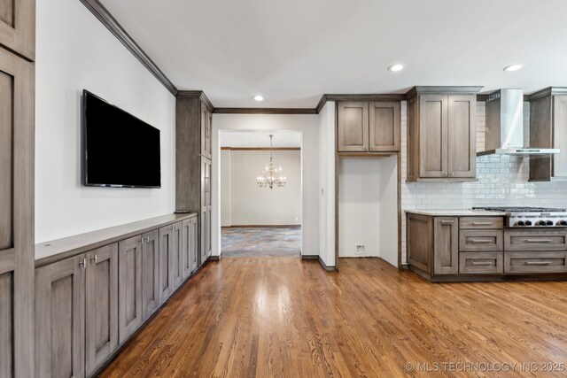 10126 S Granite Ave, Tulsa, OK 74137 - kitchen with wall chimney exhaust hood, stainless steel gas stovetop, crown molding, a chandelier, and backsplash