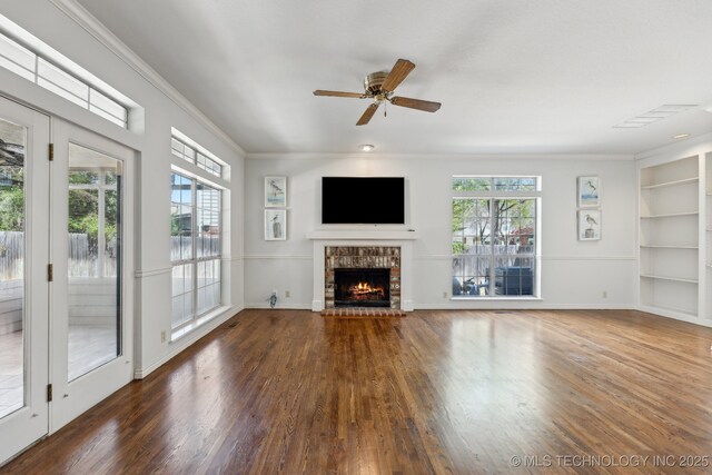 10126 S Granite Ave, Tulsa, OK 74137 - unfurnished living room featuring a brick fireplace, wood finished floors, built in shelves, ornamental molding, and ceiling fan