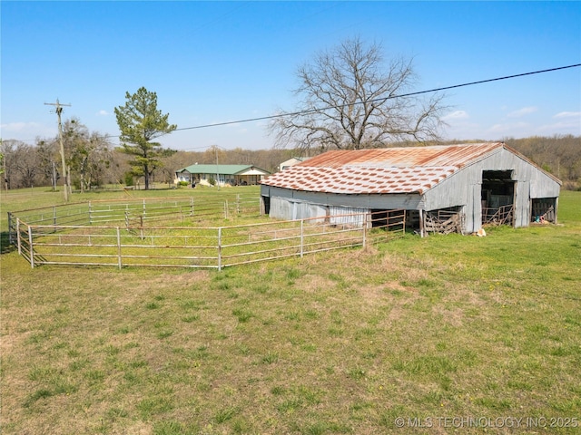 view of yard featuring an outdoor structure, a rural view, fence, and an outbuilding