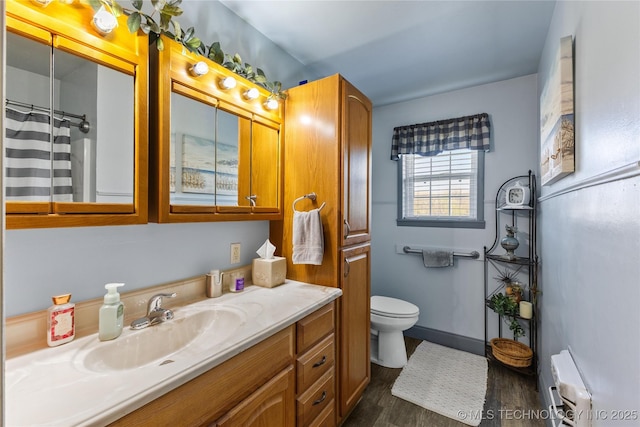 bathroom featuring vanity, radiator heating unit, toilet, wood finished floors, and baseboards