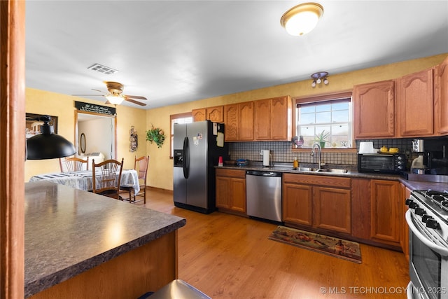 kitchen featuring visible vents, a sink, appliances with stainless steel finishes, dark countertops, and decorative backsplash