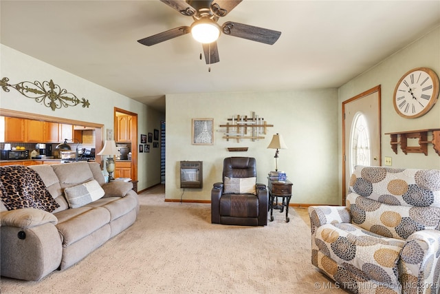 living room with baseboards, a ceiling fan, heating unit, and light colored carpet
