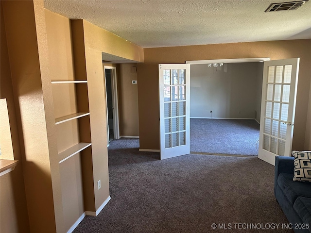carpeted empty room with french doors, baseboards, visible vents, and a textured ceiling