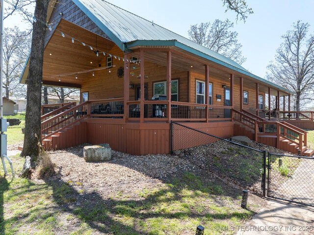 view of side of property featuring stairs, metal roof, fence, and a porch