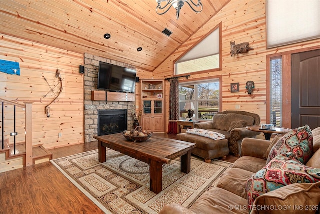 living area featuring high vaulted ceiling, a stone fireplace, wood ceiling, wood finished floors, and wooden walls