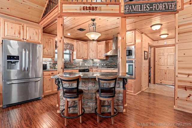 kitchen featuring wall chimney exhaust hood, light brown cabinetry, wood ceiling, appliances with stainless steel finishes, and decorative backsplash