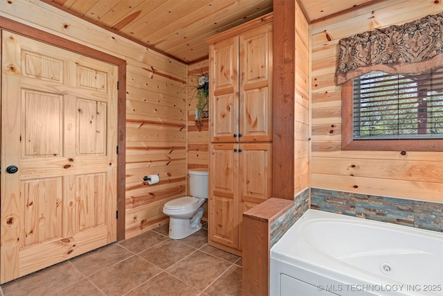 full bath with wood walls, tile patterned flooring, toilet, and a tub with jets