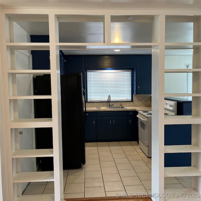 kitchen with light tile patterned floors, freestanding refrigerator, light countertops, a sink, and white electric stove
